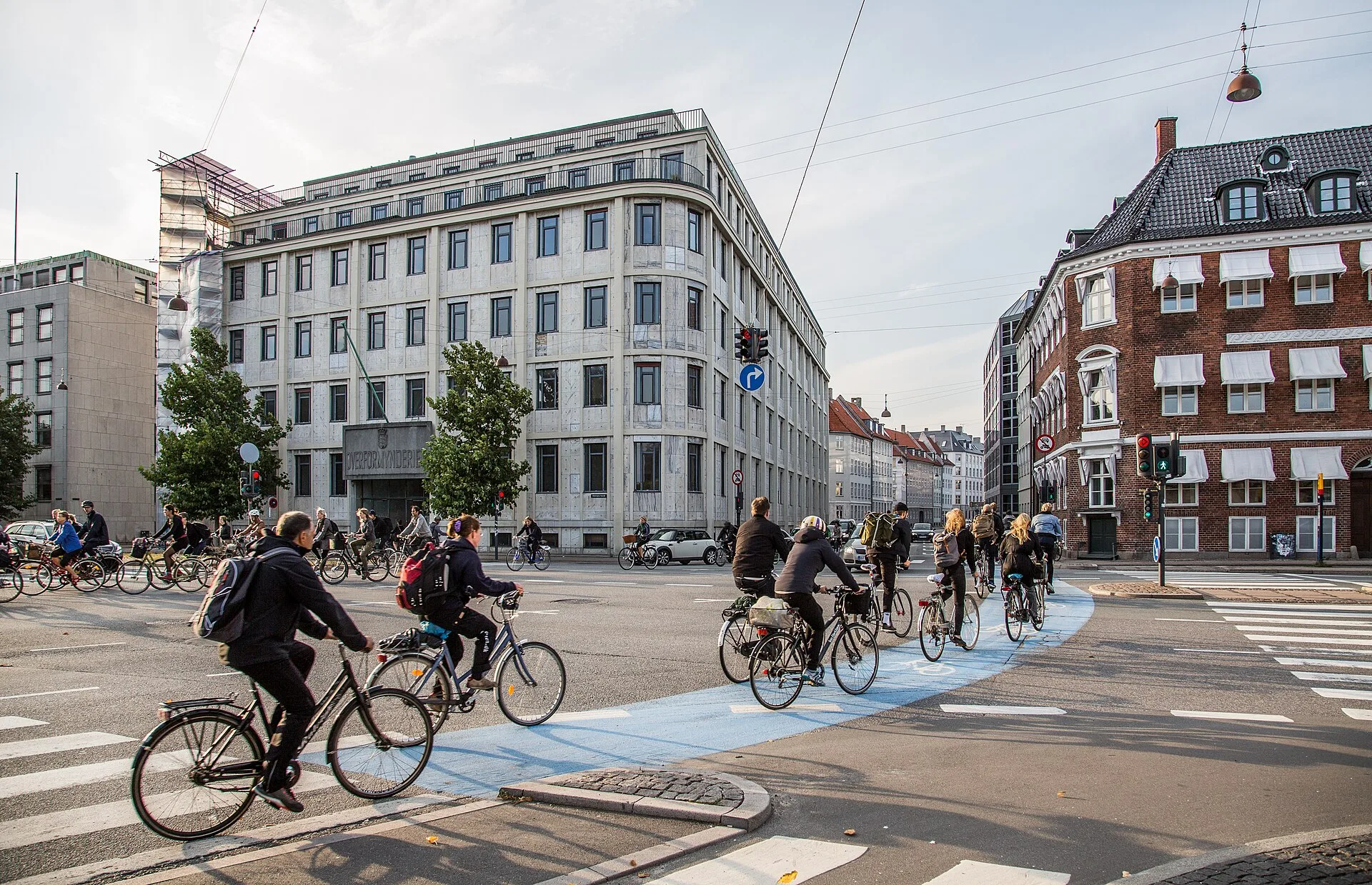 A crowd of cyclists riding through a busy intersection in Copenhagen, Denmark