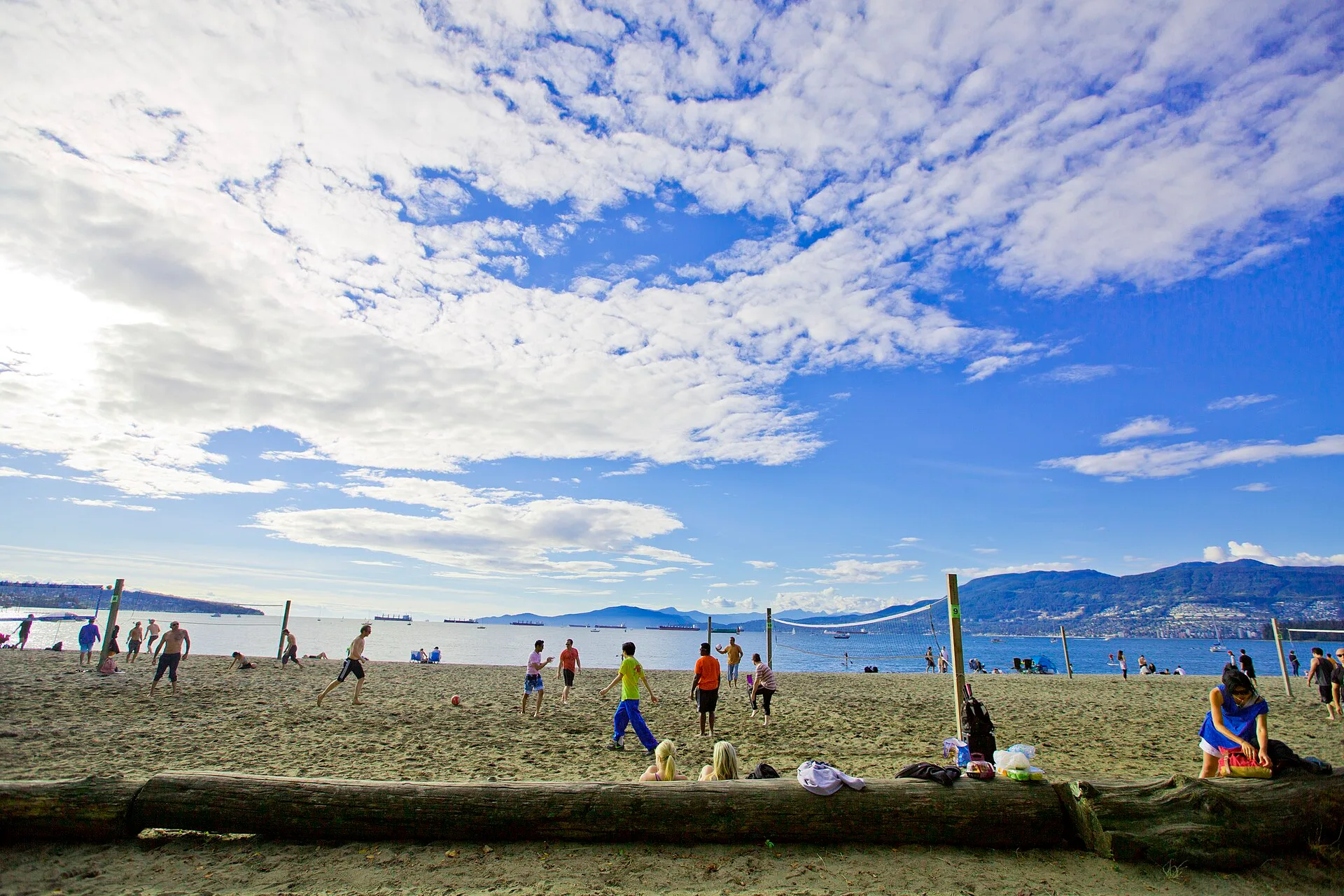 People playing beach volleyball on the sand at Kitsilano Beach in Vancouver, Canada