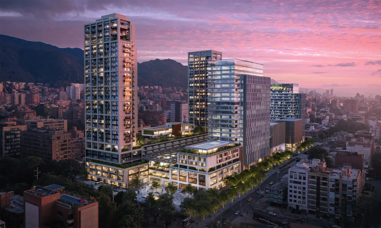 New mixed-use residential towers in Bogotá glowing at dusk with the Andes mountains behind under a pink sky