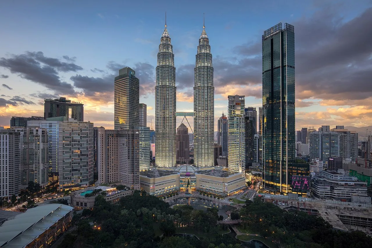 The Petronas Twin Towers glowing at dusk above KLCC Park in Kuala Lumpur