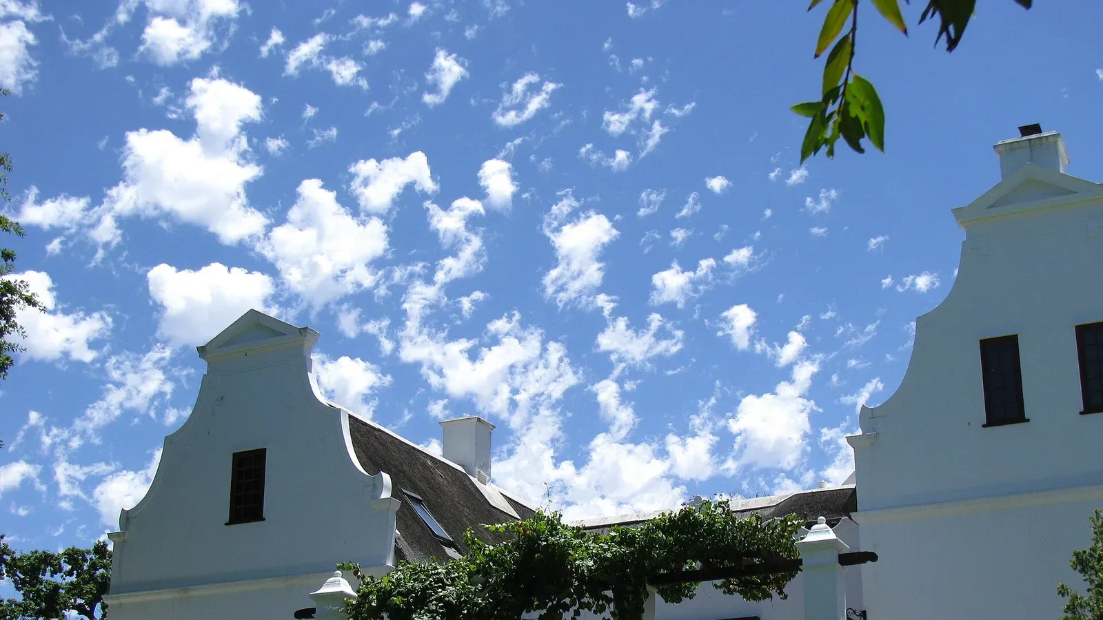 The white gabled facade of a historic Cape Dutch farmhouse (Vrede en Lust) in the Cape Winelands, South Africa