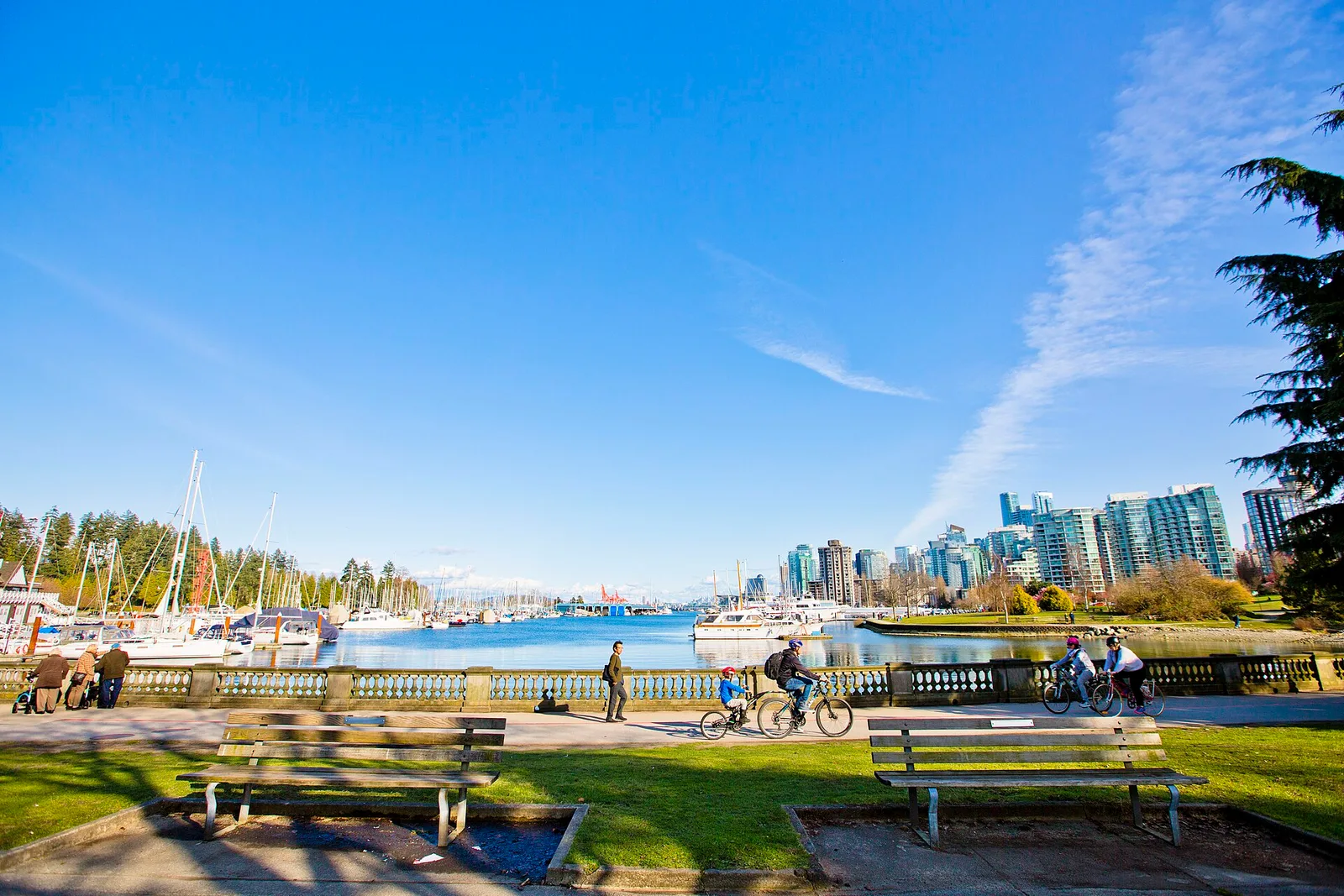 The Stanley Park seawall path beside the harbour with mountains behind in Vancouver, Canada