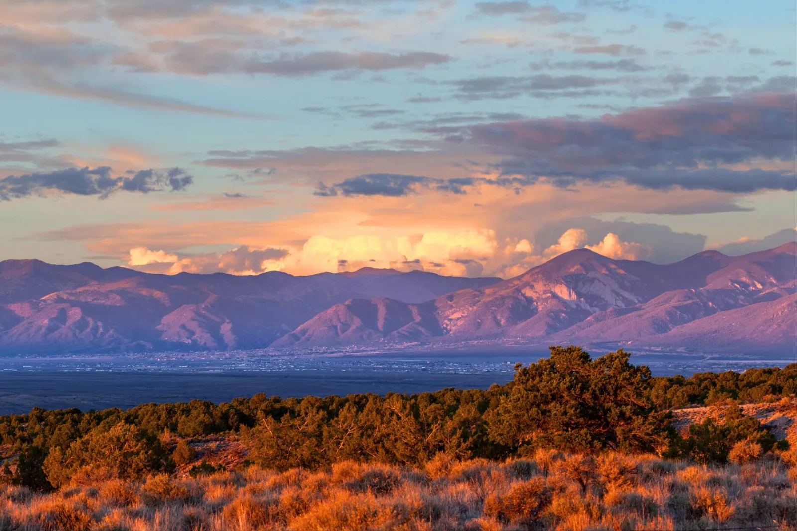 The Sangre de Cristo Mountains at sunset above high-desert sagebrush with dramatic storm clouds near Taos, New Mexico